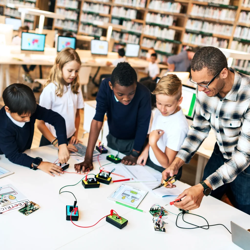 Science tutoring session with students conducting a hands on physics and electronics experiment in a classroom lab setting.